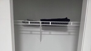 A white closet with a metal shelf on top and a white door. - The Cozy Corner Home (Winnipeg)