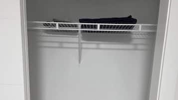 Un armario blanco con un estante metálico en la parte superior y una puerta blanca.