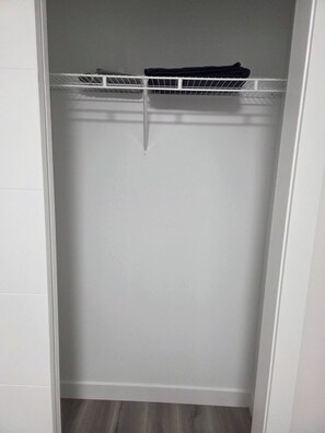 Un placard blanc avec une étagère en métal sur le dessus et une porte blanche.