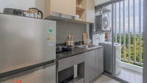 A modern kitchen with stainless steel appliances, a built-in oven, and a large window overlooking a balcony. - Mountain View Condo by Bang Tao Beach-MynaC289 (ตำบลเชิงทะเล)
