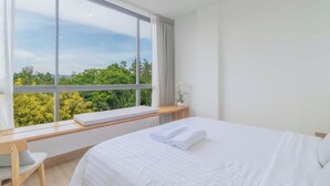 A bedroom with a large window, a bed, a bedside table, and a chair. - Mountain View Condo by Bang Tao Beach-MynaC289 (ตำบลเชิงทะเล)