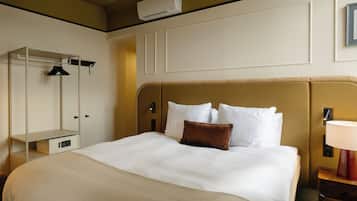 Een hotelkamer met een groot bed, een kledingkast, een nachtkastje met lamp en een airconditioning op de muur.