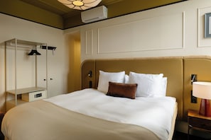 A hotel room with a large bed, a wardrobe, a bedside table with a lamp, and an air conditioning unit on the wall. - Kasteel Doenrade - digital check-in, key by email or SMS (Doenrade)