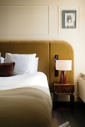 A neatly made bed with white linens and a brown headboard. There is a bedside table with a lamp and a framed picture on the wall above. - Kasteel Doenrade - digital check-in, key by email or SMS (Doenrade)