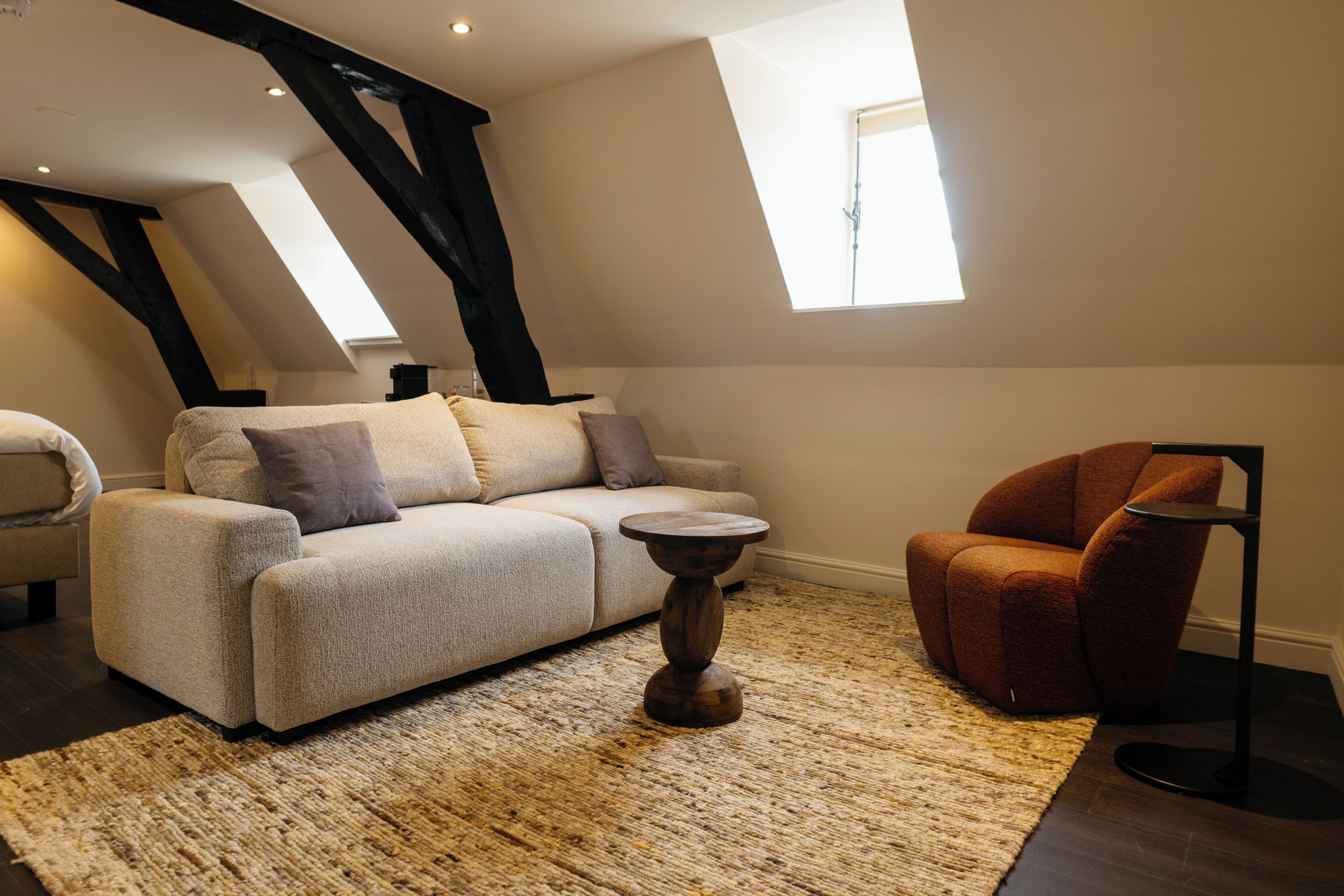 A loft-style living room with a sofa, a wooden coffee table, and a red armchair.