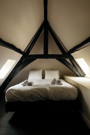 A bedroom with a sloped ceiling, a bed with white linens, and two skylights. - Kasteel Doenrade - digital check-in, key by email or SMS (Doenrade)