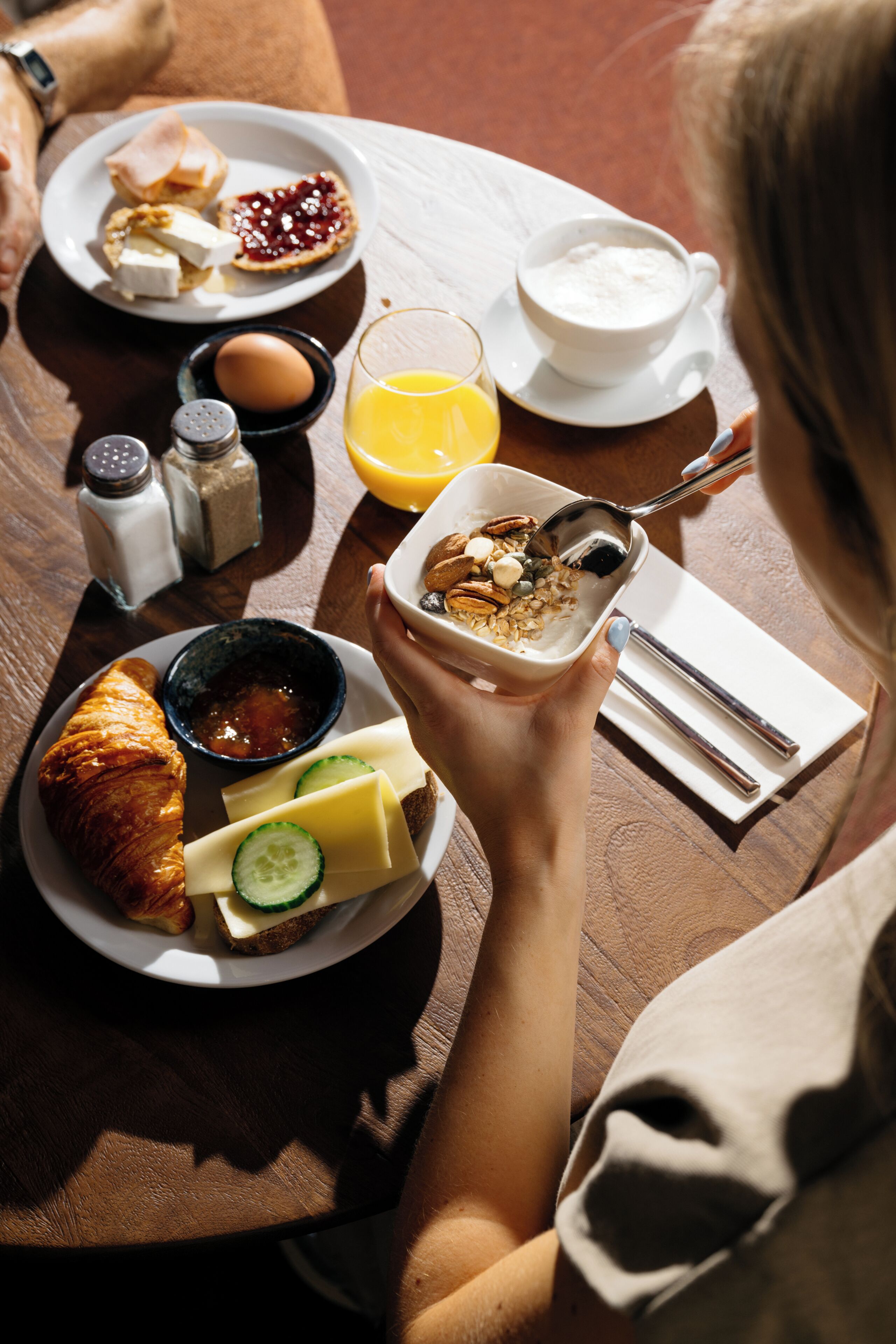 Una mesa de comedor con un plato de comida, un tazón de cereal, un vaso de jugo de naranja y una taza de leche.