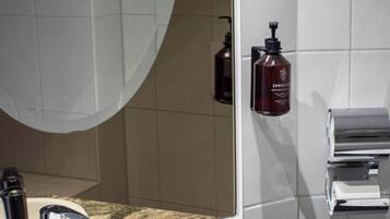 A bathroom with a sink, mirror, towel rack, and toiletries.