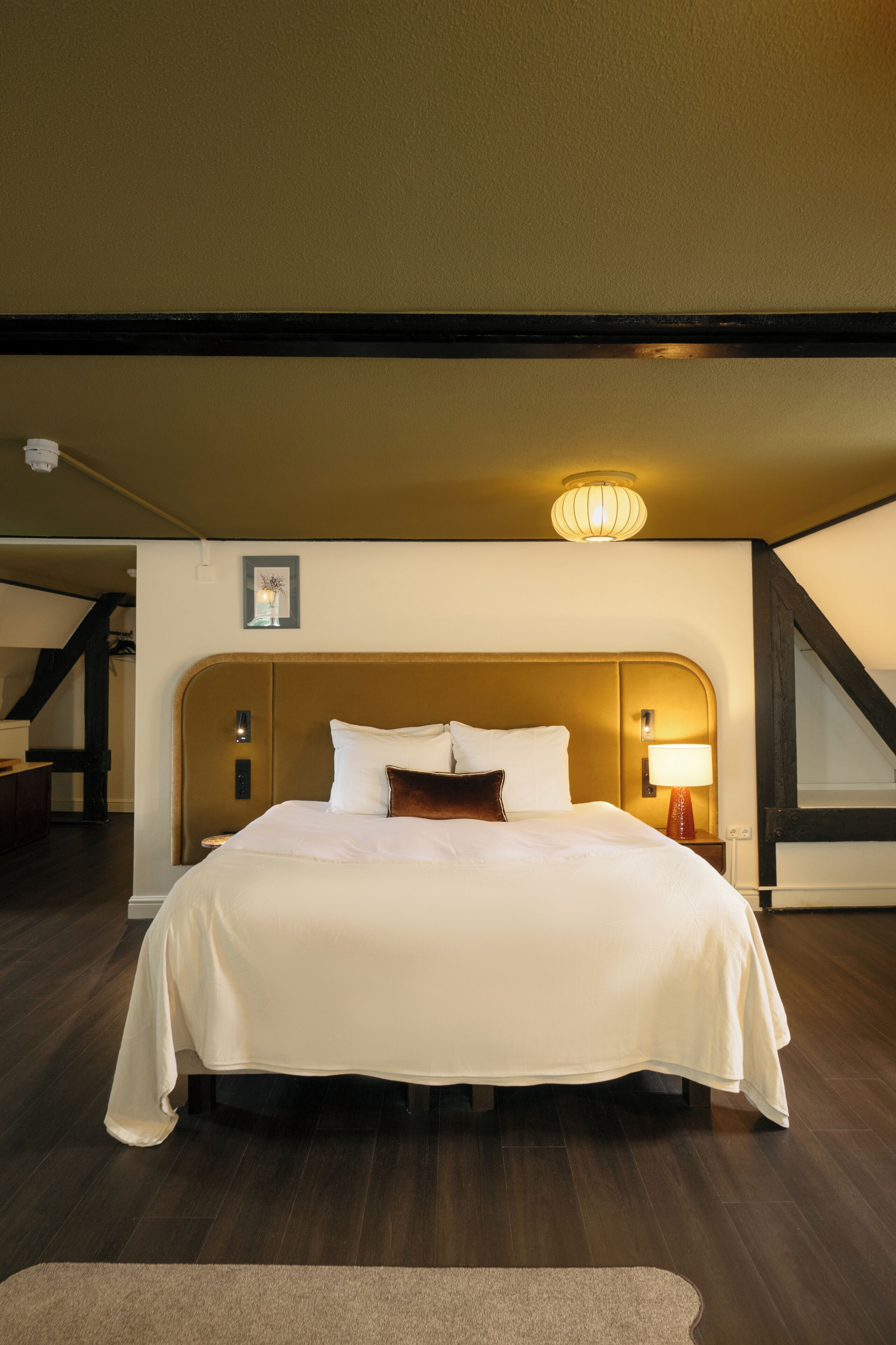 Ein Hotelzimmer mit einem großen Bett, einem Nachttisch, einer Wandlampe und einer Deckenleuchte.