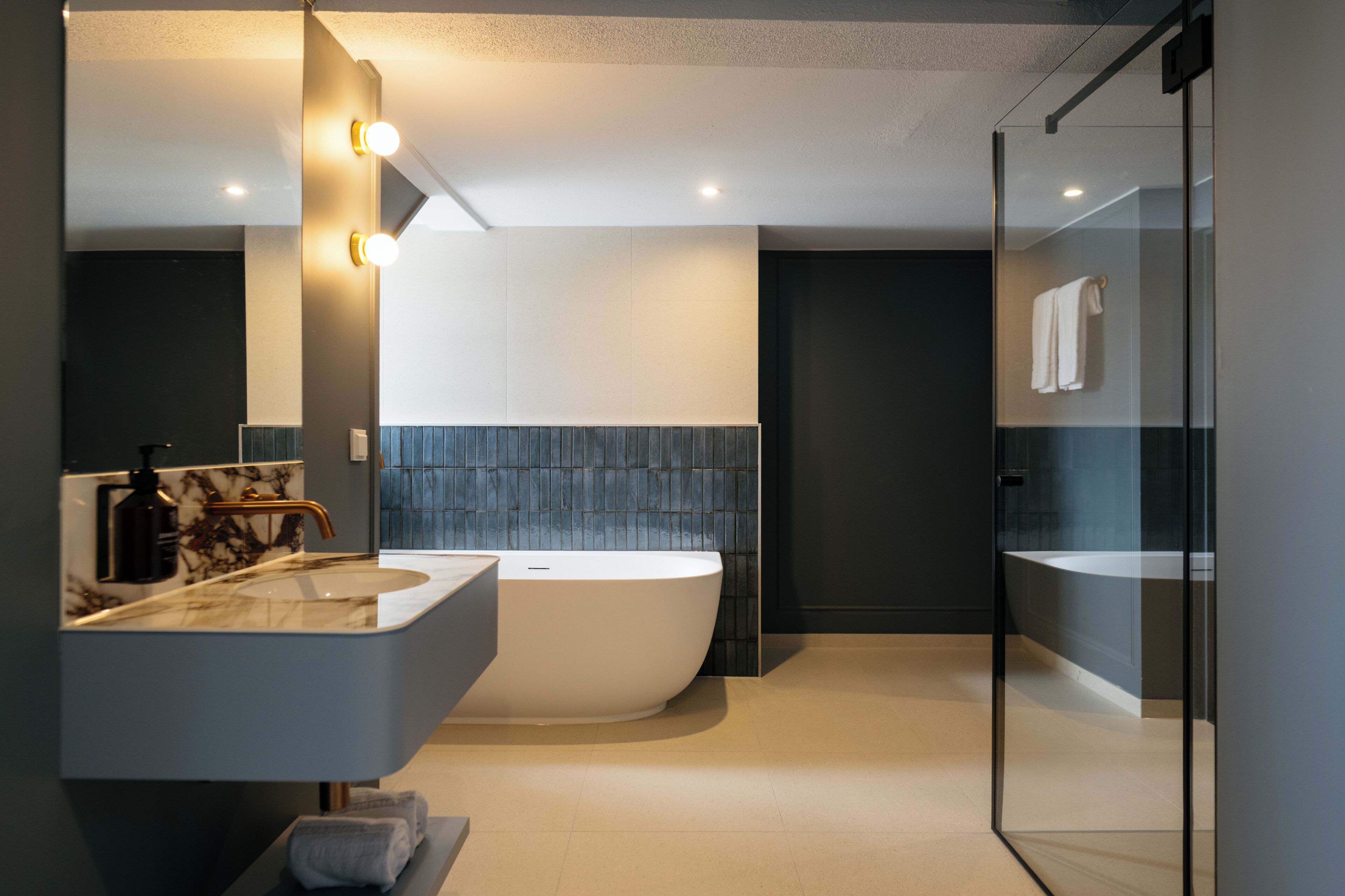 Ein modernes Badezimmer mit freistehender Badewanne, einem großen Spiegel und einer Dusche mit Glaswand.