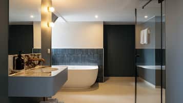 Ein modernes Badezimmer mit freistehender Badewanne, einem großen Spiegel und einer Dusche mit Glaswand.