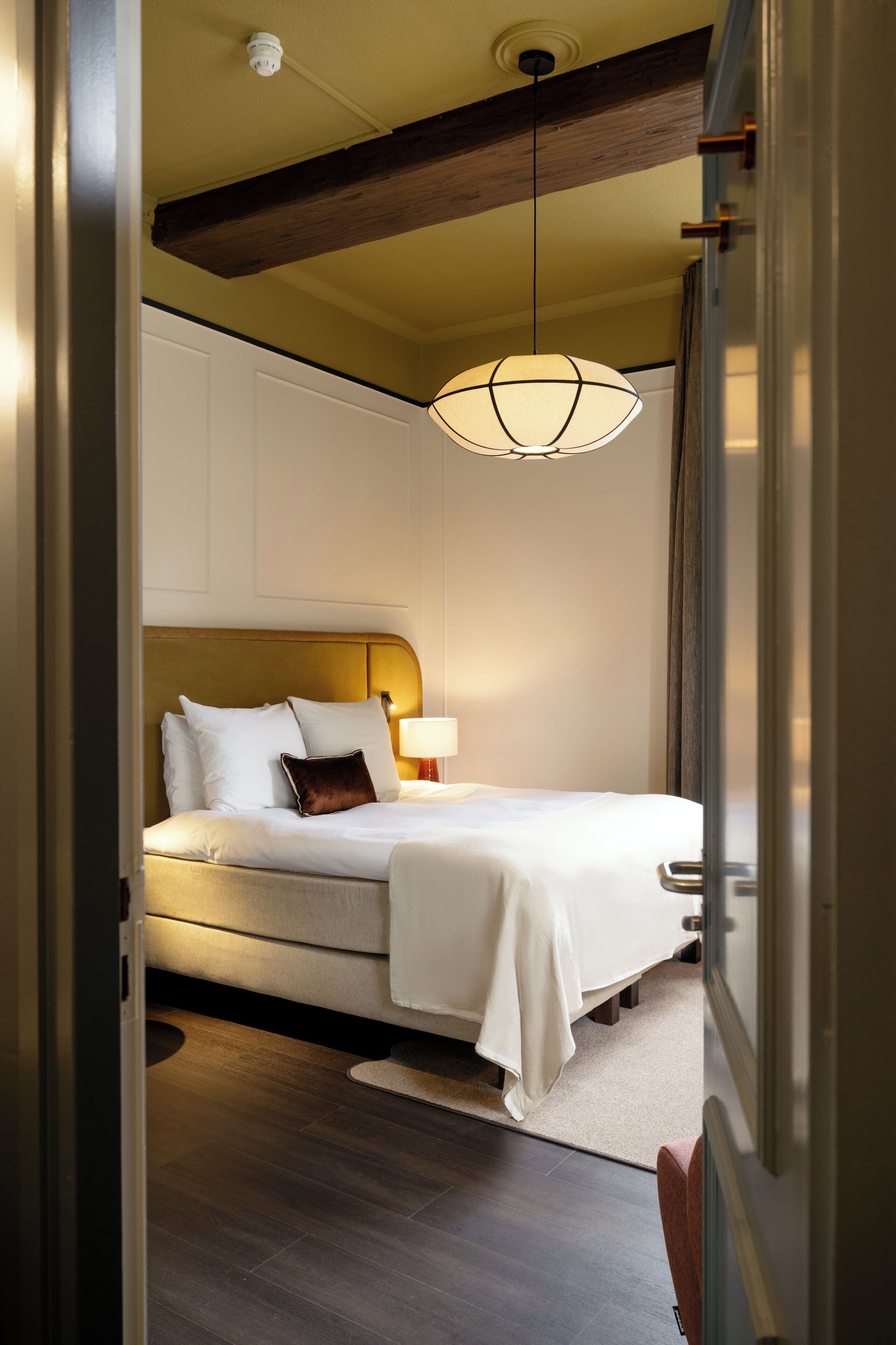 Une chambre à coucher avec un lit, une table de chevet, une lampe et un luminaire suspendu.
