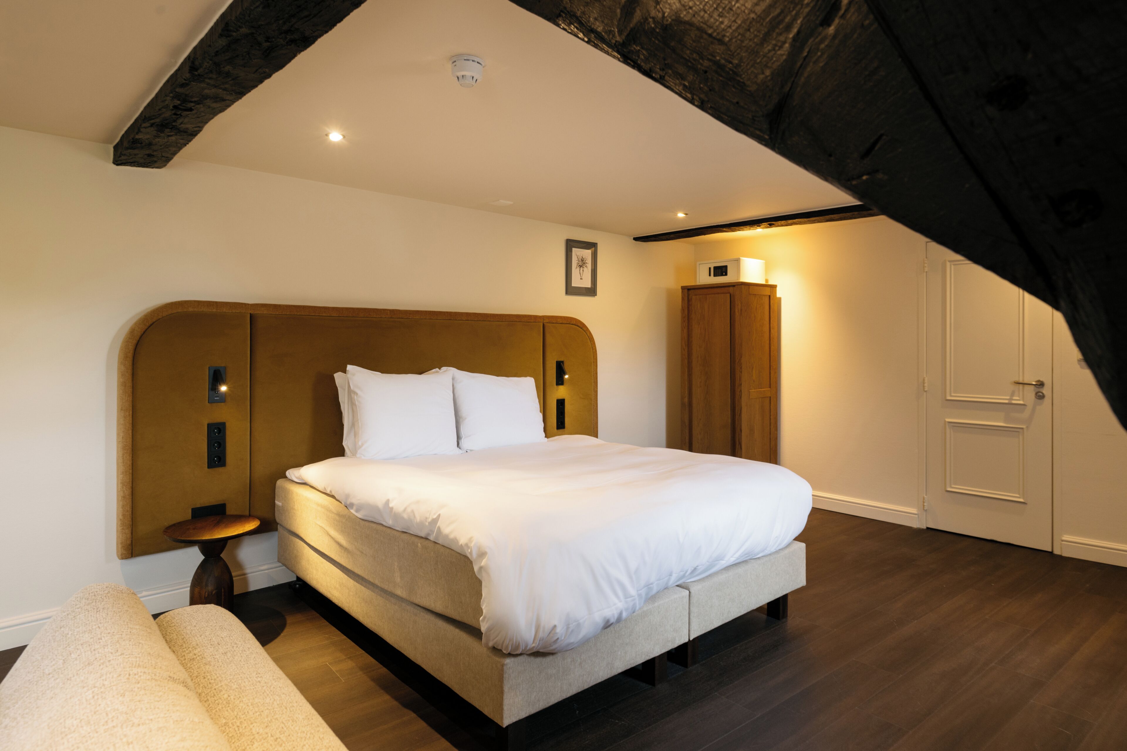 Een slaapkamer met een groot bed, nachtkastje, kledingkast en een deur.