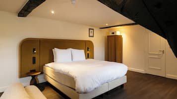 Een slaapkamer met een groot bed, nachtkastje, kledingkast en een deur.