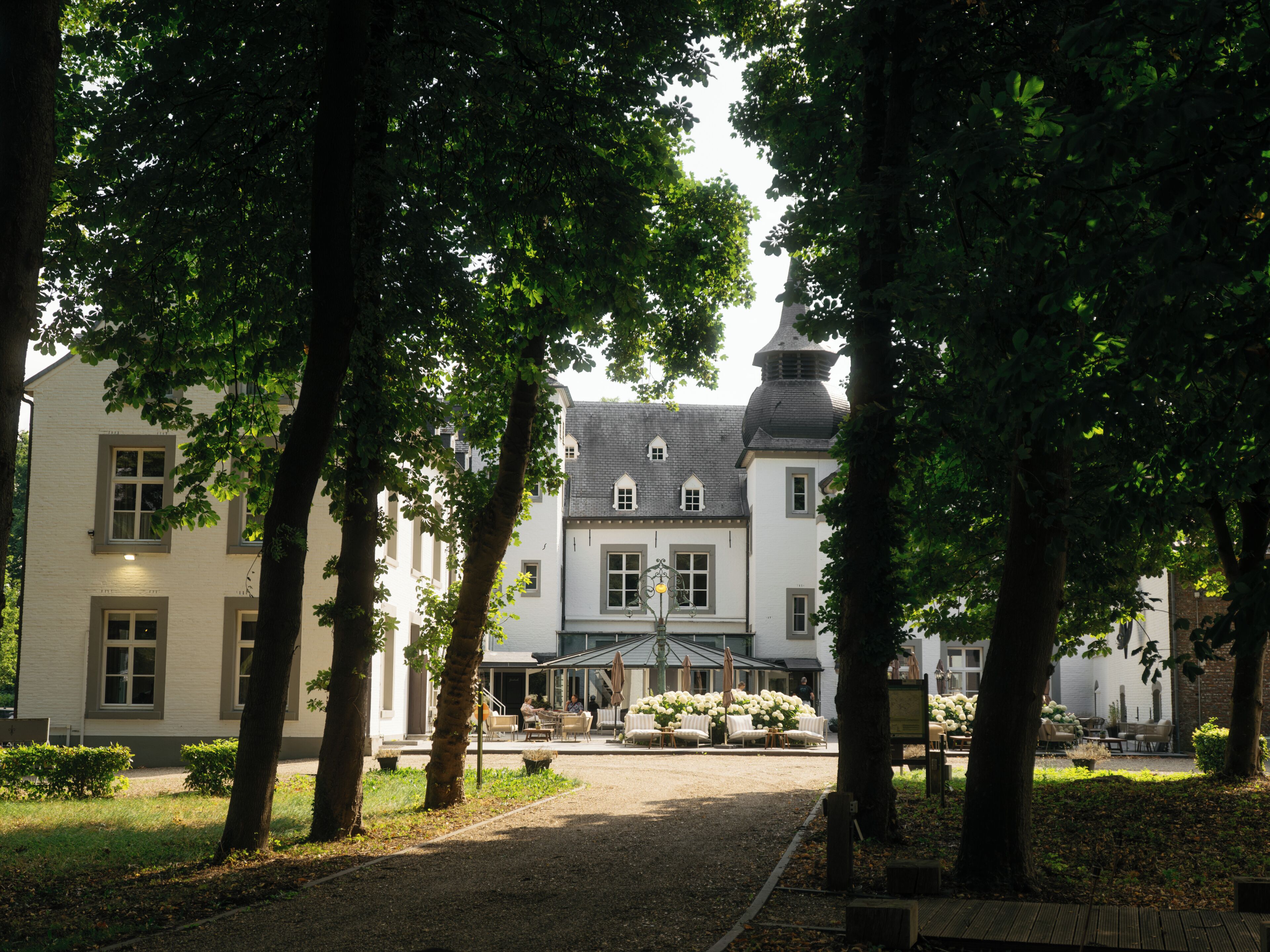 Une cour intérieure avec un bâtiment en arrière-plan, entourée d’arbres.
