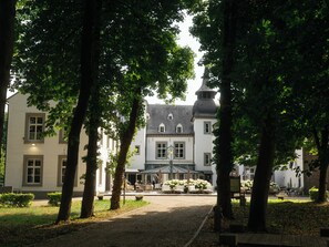 A courtyard with a building in the background, surrounded by trees. - Kasteel Doenrade - digital check-in, key by email or SMS (Doenrade)