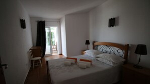A bedroom with a bed, two bedside tables, a chair, and a window with curtains. - CASA 8 - Sea View T3 (Luz)
