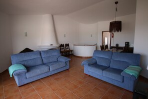 Ein Wohnzimmer mit zwei blauen Sofas, einem weißen Couchtisch und einer großen weißen Kommode.