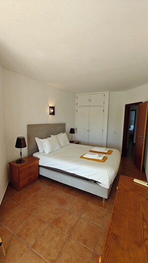 Ein Schlafzimmer mit einem Bett, Nachttischen, einem Kleiderschrank und einer Lampe.