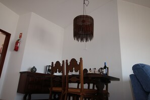 Ein Essbereich mit Tisch, Stühlen, einer Pendelleuchte und einem an der Wand befestigten Feuerlöscher.