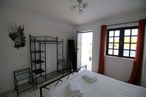 A room with a bed, a metal shelf unit, a door, and a window with curtains. - VILLA VANGOH T2 Sunnypool (Luz)