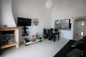 A modern living room with a flat-screen TV, a glass coffee table, a sofa, and a dining area with chairs and a glass table. - VILLA VANGOH T2 Sunnypool (Luz)