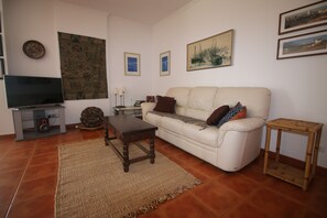 Ein Wohnzimmer mit einer Couch, einem Couchtisch, einem Fernseher und gerahmten Bildern an der Wand.