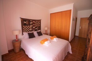 Ein Hotelzimmer mit einem großen Bett, zwei Nachttischen, einer Wandteppich und einem Holzschrank.