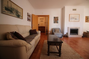 Ein Wohnzimmer mit einer Couch, einem Couchtisch, einem Kamin und Kunstwerken an den Wänden.