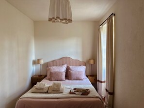 Un lit bien fait, avec des oreillers, une lampe de chevet et un plateau contenant divers objets posé sur le lit.