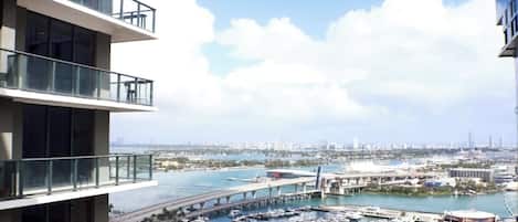 Un immeuble de grande hauteur doté de nombreux balcons, offrant une vue sur un port de plaisance et un pont.