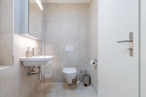Ein modernes Badezimmer mit Toilette, Waschbecken und einer Duschkabine aus Glas.