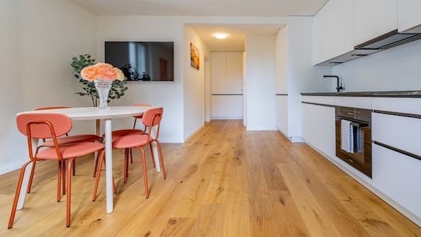 Eine moderne Küche mit Essbereich, Holzboden und einem an der Wand befestigten Flachbildfernseher.