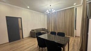 Una habitació amb taula de menjador, cadires, sofà i cortines.