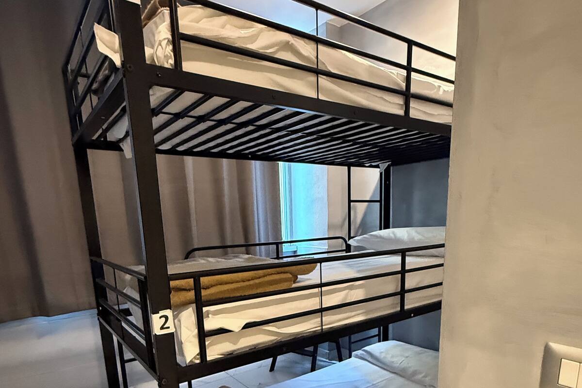 Ein Stockbett mit drei Etagen, nummeriert von 1 bis 3, in einem Zimmer mit Fliesenboden und einem fenster mit Vorhängen.