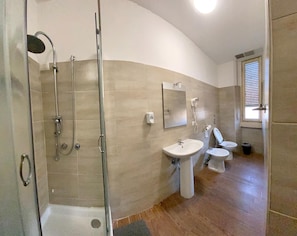 A bathroom with a glass shower enclosure, a sink, a toilet, and a bidet. - Monkey Hostel Milano (Milan)