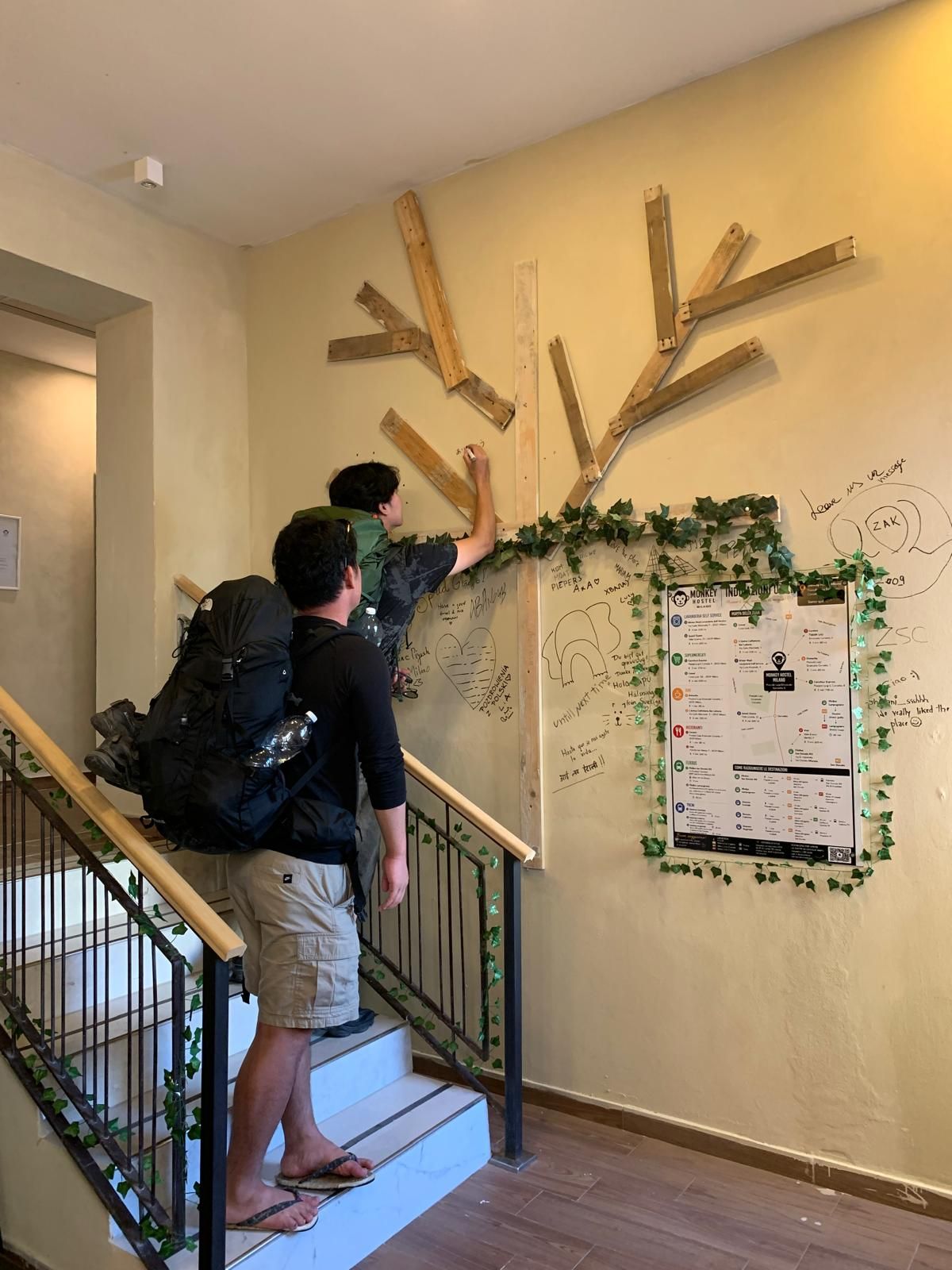 Una scala con travi in legno e un muro ricoperto di scritte e disegni a mano.