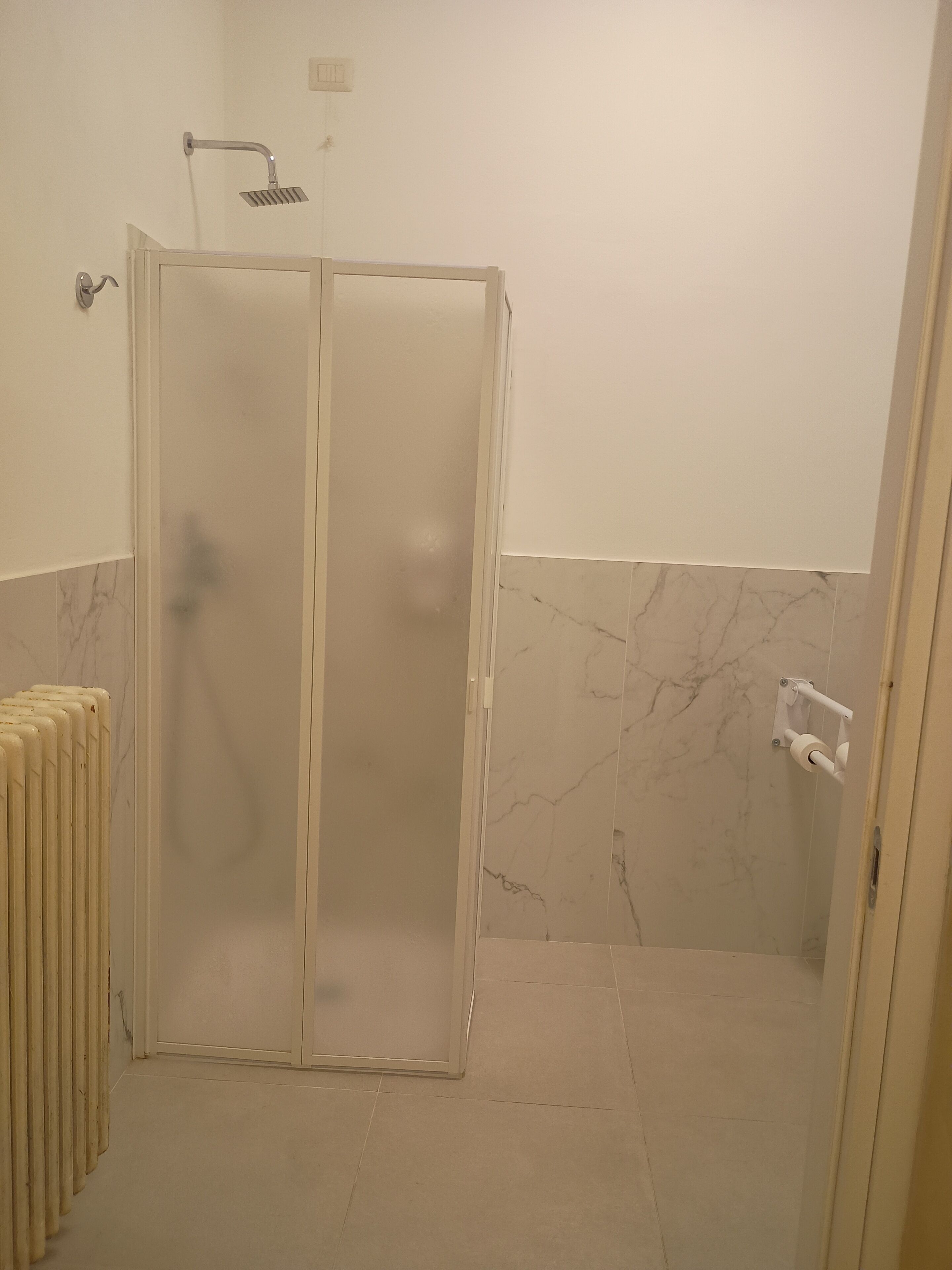 Ein Badezimmer mit Duschkabine, Toilette und Handtuchwärmer.