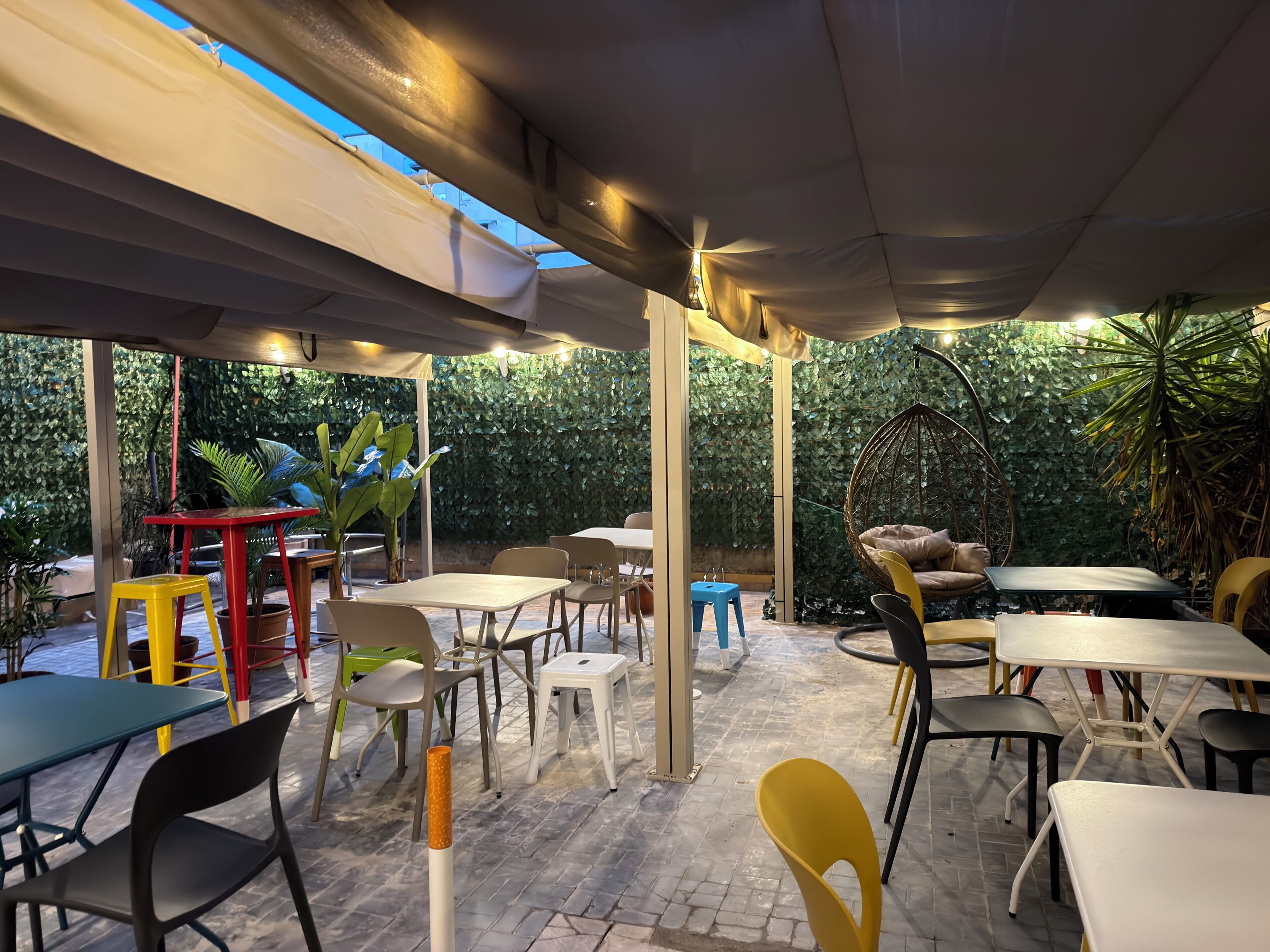 Un área con mesas y sillas para disfrutar al aire libre, rodeada de vegetación.