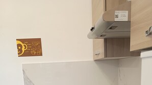Une cuisine compacte équipée d’une cuisinière à gaz, d’une bouilloire et d’un petit tabouret.