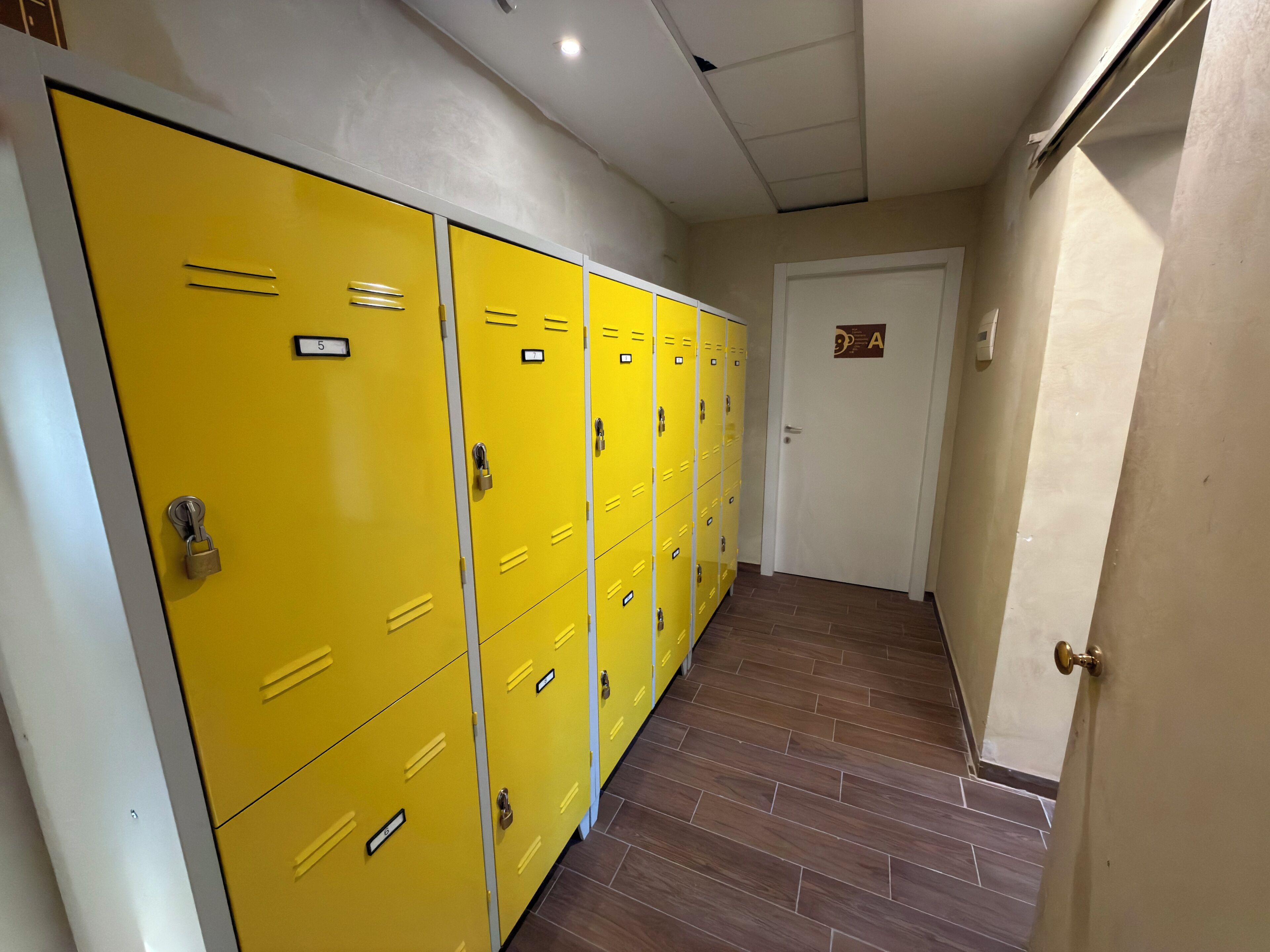 A hallway with yellow lockers and a door marked with an 'A' sign.