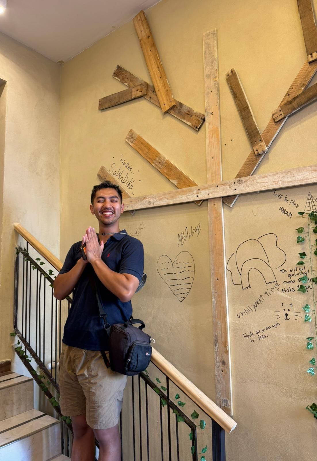 A person standing on a staircase with a wall decorated with wooden beams and handwritten messages.