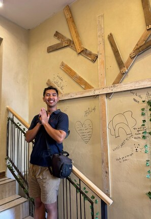 A person standing on a staircase with a wall decorated with wooden beams and handwritten messages.
