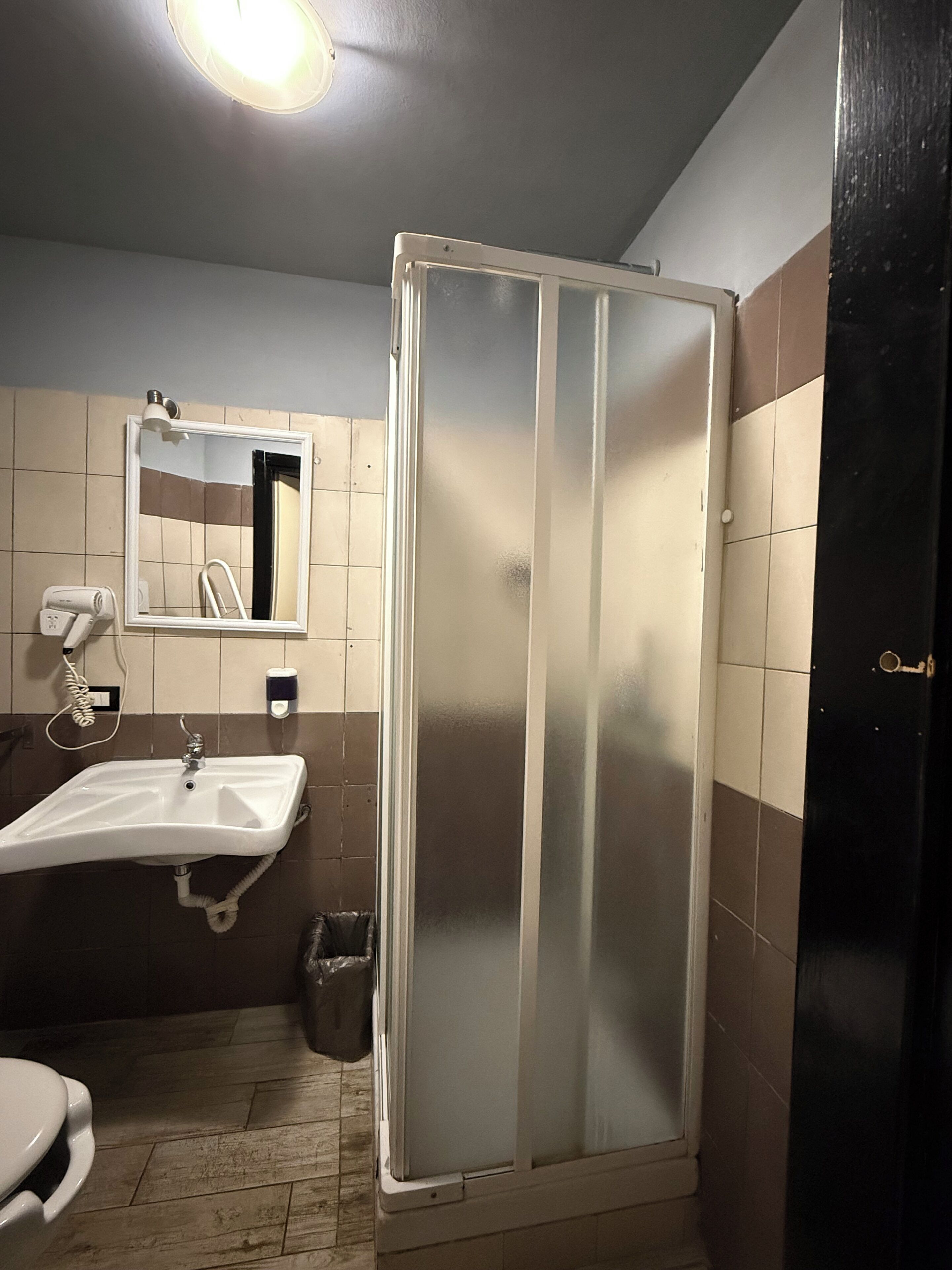 A bathroom with a sink, mirror, and shower enclosure.