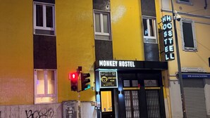Un bâtiment avec une enseigne indiquant « Monkey Hostel » et un panneau néon indiquant « HooSTeLL ».