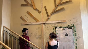 Una scala con travi in legno e un muro con diverse scritte e una bacheca dei menu.