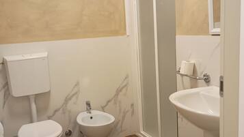 A bathroom with a toilet, bidet, and sink.