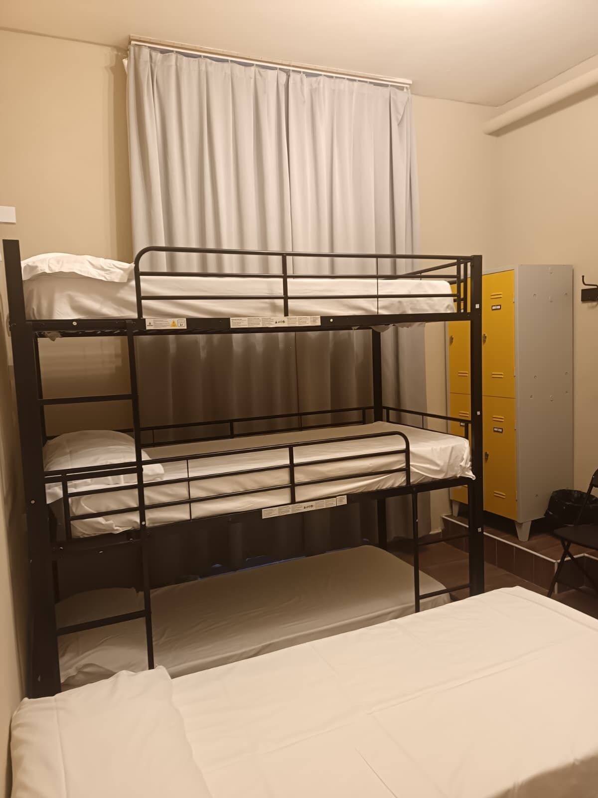 A bunk bed room with a curtain, a chair, and a set of lockers.