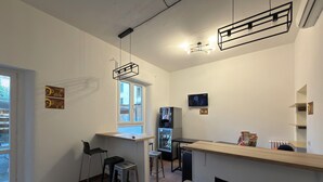 Une cuisine moderne avec un plan de travail en bois, des tabourets de bar, un réfrigérateur encastré et un téléviseur fixé au mur.