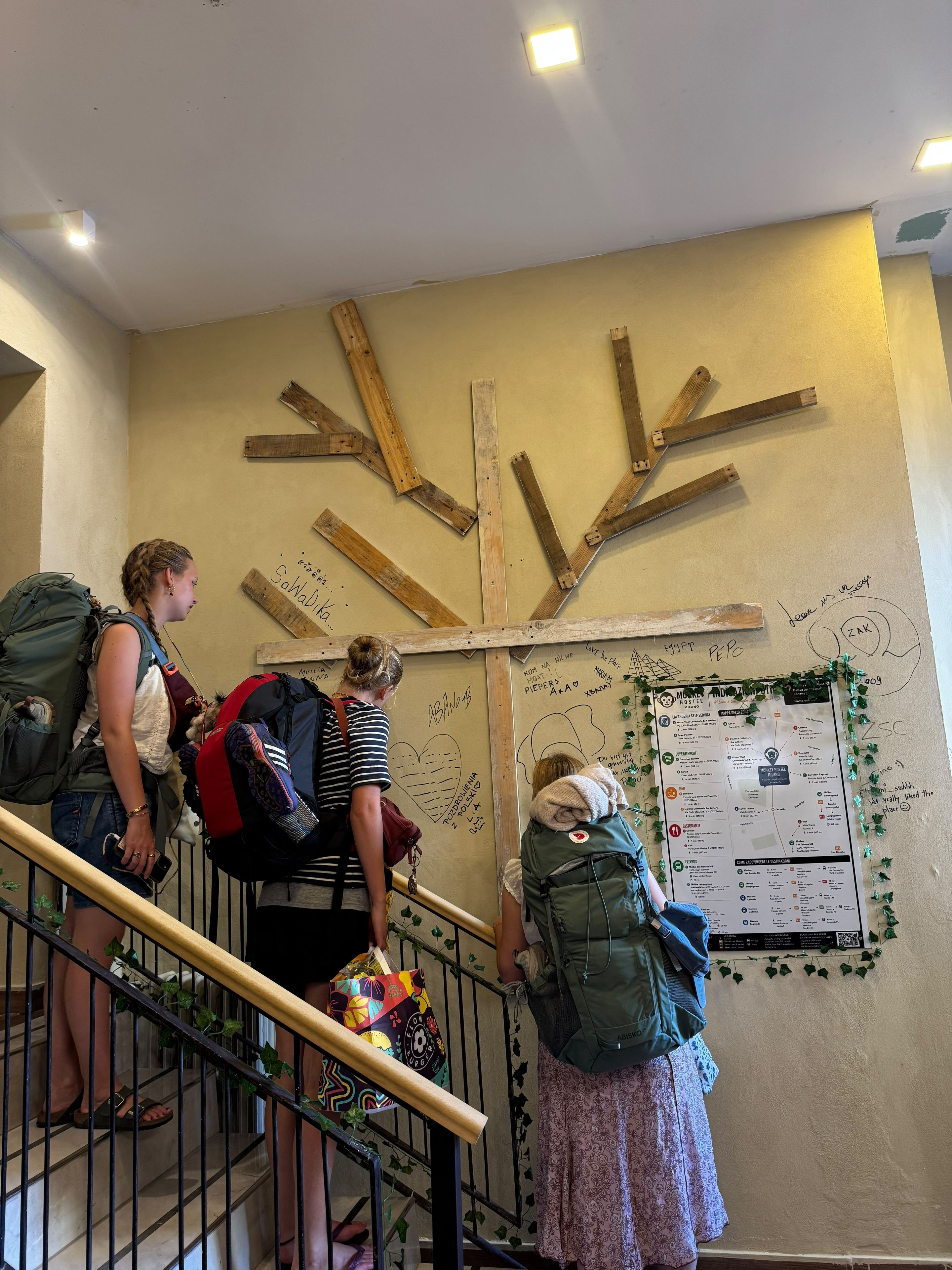 A staircase with a wooden handrail and a wall with a bulletin board and wooden beams.